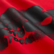 Close-up view of the bold black graphic print detail on the red Sp5der Moto 5 Tee streetwear shirt fabric.