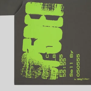 Close-up of the Sp5der Commerce Tee featuring vibrant neon green distressed graphic print on a dark grey cotton fabric.
