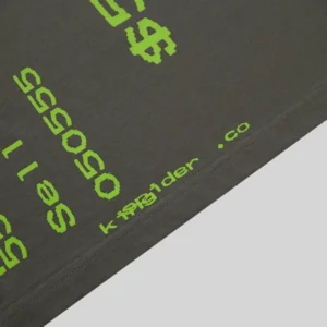 Close-up view of the Sp5der Commerce Tee in slate grey featuring vibrant neon green pixelated graphic print details.