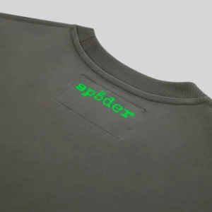 Close-up of the Sp5der Fingerprint Tee featuring the vibrant green logo on dark gray charcoal cotton fabric.