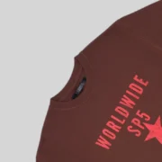 Close up of the brown Sp5der Oversized Worldwide Sp5 T-shirt featuring bright red text and star graphic details.