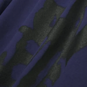 Close-up view of the Sp5der SP5 5Luminum Tee featuring a bold black spray-paint graphic print on a dark blue fabric.