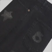 A close-up view of the black Sp5der Beluga denim shorts showcasing the detailed fabric texture and star design patterns.