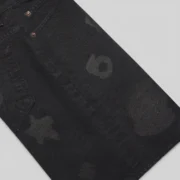 Close-up view of the Sp5der Beluga Denim Short in Black, highlighting the premium 100% cotton fabric and faded print details.