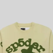 Close up view of the Sp5der Beluga long sleeve shirt in tan featuring the signature graphic print detail on the front.