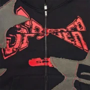 Close-up of the Sp5der Big Star Full Zip Hoodie in black, featuring distressed frayed star patches and graphic print.