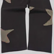 Close up view of the black Sp5der Big Star sweatpants featuring unique frayed star patch details on the fabric.
