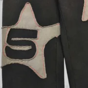 Close-up of the frayed star patch detail on the black Sp5der Big Star cotton fleece sweatpants for men and women.