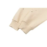 Close-up view of the elasticated ribbed cuffs on the Sp5der Cropped Sweatpant in the Cream colorway with star details.