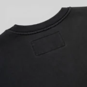 Close-up view of the ribbed knit collar and neckline detail on the black Sp5der Diffused Collegiate Crewneck sweatshirt.