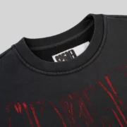 Close-up view of the black Sp5der Diffused Collegiate Crewneck featuring the brand label and red graphic print detail.