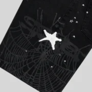 Close-up view of the Sp5der Black Heavy Web Denim Short featuring a large white spider web graphic and star print.