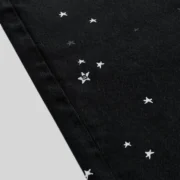 Close-up view of the black Sp5der Heavy Web Denim Shorts featuring a unique scattered star graphic print detail.