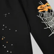 Close-up detail of the black Sp5der Heavy Web sweatpants featuring the signature puff print web and scattered star graphic.