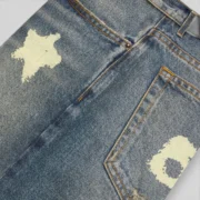 A close-up view of the Sp5der Indigo Beluga Denim Short in blue, showcasing the unique graphic print and heavy cotton.