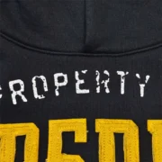 Close-up view of the Sp5der Issue 404 black hoodie featuring raised yellow chenille-style lettering and cracked graphic.