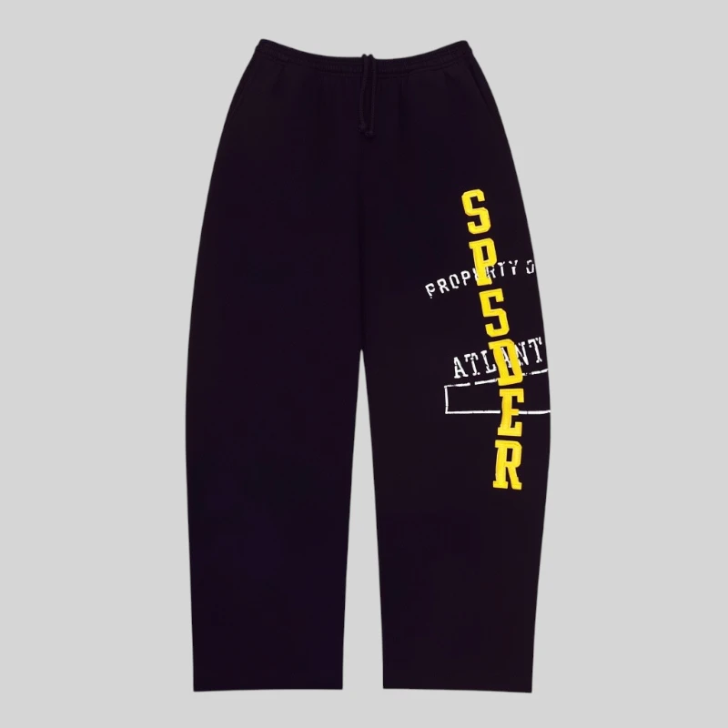 Front view of black Sp5der Issue 404 sweatpants featuring yellow vertical text and white graphic print details.