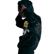 A person wearing the black Sp5der Jeffery hoodie with star print and logo in a side profile view against white background.