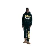 Model wearing a black Sp5der Jeffery hoodie and matching sweatpants set with urban street style print design.