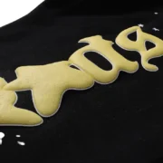 Close-up view of the Sp5der Jeffery sweatpant in black showing the premium quality yellow puffed branding logo detail.