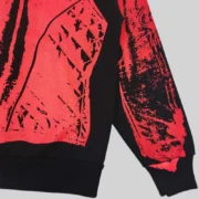 Close-up view of the bold, red painted moto graphic print detail on the black Sp5der JP5 Moto Hoodie fleece fabric.