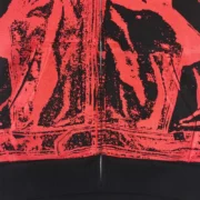 Close-up view of the black and red Sp5der JP5 Moto Hoodie graphic print detail on the front zip-up sweatshirt.