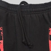 Close-up view of the black Sp5der JP5 Moto sweatpants showing the elastic waistband, drawstrings, and painted red graphics.