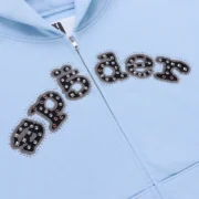 Close-up of the Sp5der Mixed Stone OG V2 Zip Hoodie in Rock Blue featuring embellished logo graphic detail.