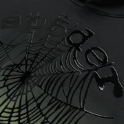 Close-up view of the Sp5der OG Web Ombre Hoodie in black featuring the signature puff print spider web graphic detail.