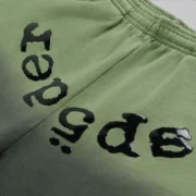 A close-up view of the black Sp5der OG Web Ombre sweatpants featuring the signature puff print branding at the crotch.