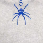 Close-up view of the Sp5der OG Web V2 Knicks Home Hoodie in grey, highlighting the signature blue spider web logo graphic.