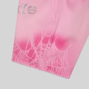 Close-up of Sp5der OG Web V2 Spray Zip Shorts in Light Pink featuring iconic rhinestone SP5DER text and web graphic.