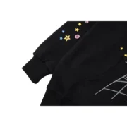 Close up view of the black Sp5der P*NK hoodie sleeve featuring detailed colorful star graphics and iconic branding.