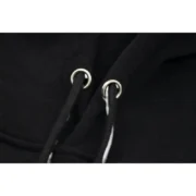 Close-up view of the drawstring and eyelet details on the black Sp5der P*NK hooded sweatshirt fabric.