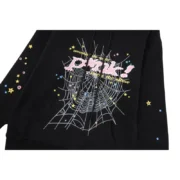 Close-up view of the black Sp5der P*NK hoodie featuring a signature spiderweb graphic and colorful star accents.