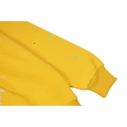 Close-up of the premium mustard-yellow fabric texture on the Sp5der P*NK collaboration hoodie sleeve.