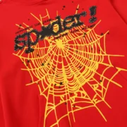 Close-up view of the Sp5der P*NK V2 Hoodie in red, featuring signature black puff print branding and yellow web graphics.