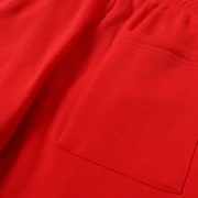 Close-up view of the premium red cotton fleece fabric and pocket detail of the Sp5der P*NK V2 streetwear sweatpants.