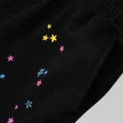 Close-up view of the black Sp5der Punk V2 sweatshorts featuring colorful scattered star graphic print details.
