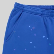 Close-up of Sp5der Rhinestone Punk V2 Blue sweatpants showing the elastic waistband and scattered star graphic print.