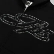 Close-up view of the Black Sp5der Rhinestone Script Full Zip Hoodie featuring sparkling rhinestone script graphics.