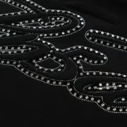 Closeup view of the sparkling rhinestone script graphic detail on the Sp5der Full Zip Hoodie in black cotton fleece.