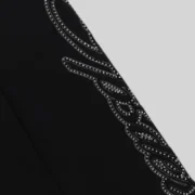 A closeup view of the premium black Sp5der sweatpants featuring a bold script logo design adorned with sparkling rhinestones.