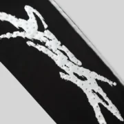 Close-up of black Sp5der Screaming Eagle sweatpants featuring detailed white rhinestone logo branding and sprayed side stripe