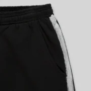 Close-up view of the black Sp5der Screaming Eagle sweatpants featuring a distinctive sprayed-effect silver side stripe.