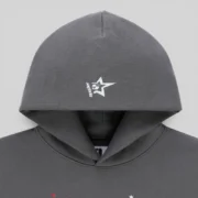 Closeup of the Slate Sp5der Splat Punk hoodie hood showing the signature white star branding detail on grey fabric.