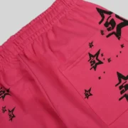 Close-up view of the Sp5der Stencil Sweatpants in a vibrant pink colorway featuring black star graphic print details.