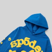 Close-up view of the Sp5der Beluga Hoodie in TC Blue featuring yellow puff print branding and star graphics on cotton.