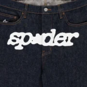 Close-up view of the white Sp5der logo graphic printed on the front of Indigo V3 heavy-duty cotton denim shorts.
