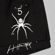 A closeup of the black Sp5der VAA double layer shorts featuring a signature white spider graphic and star details.